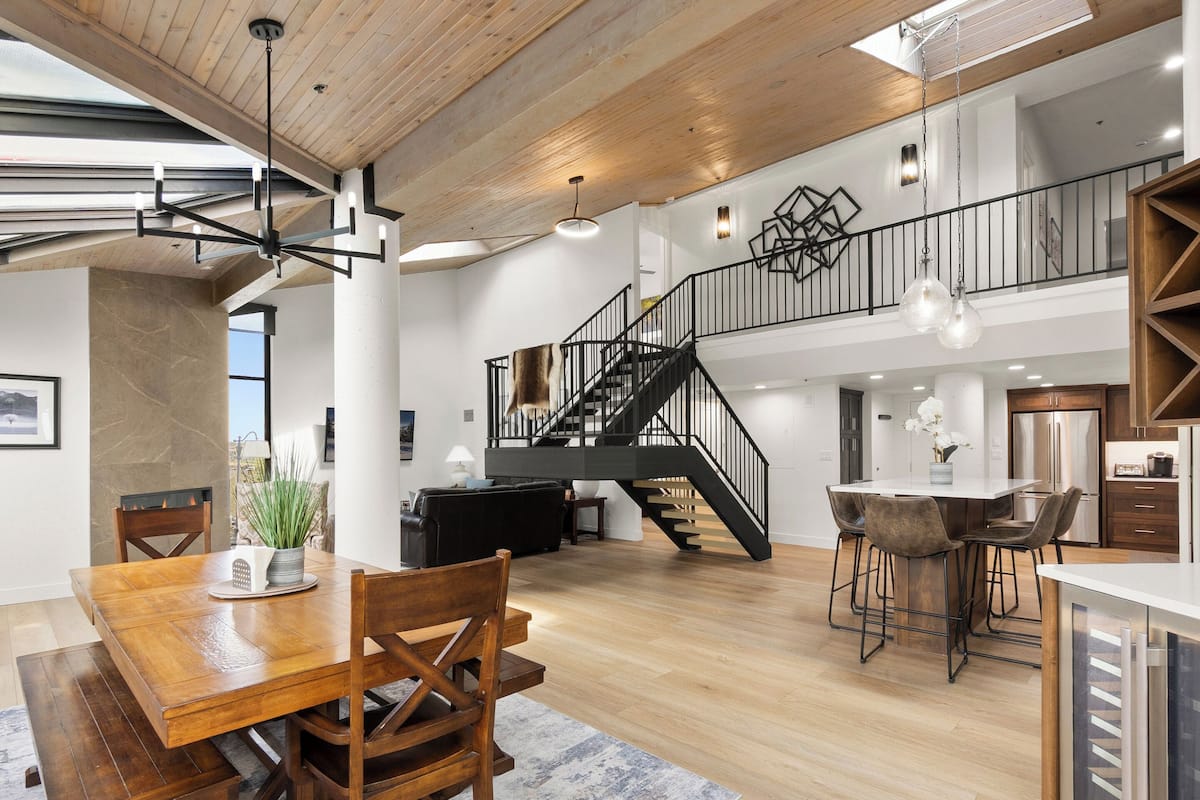 Una cocina amplia con electrodomésticos modernos, un comedor con mobiliario de madera y una escalera que conduce a un nivel superior.