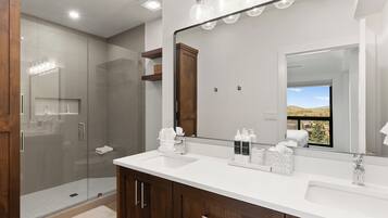 A modern bathroom with a glass shower enclosure, a large mirror, and a vanity with a white countertop.
