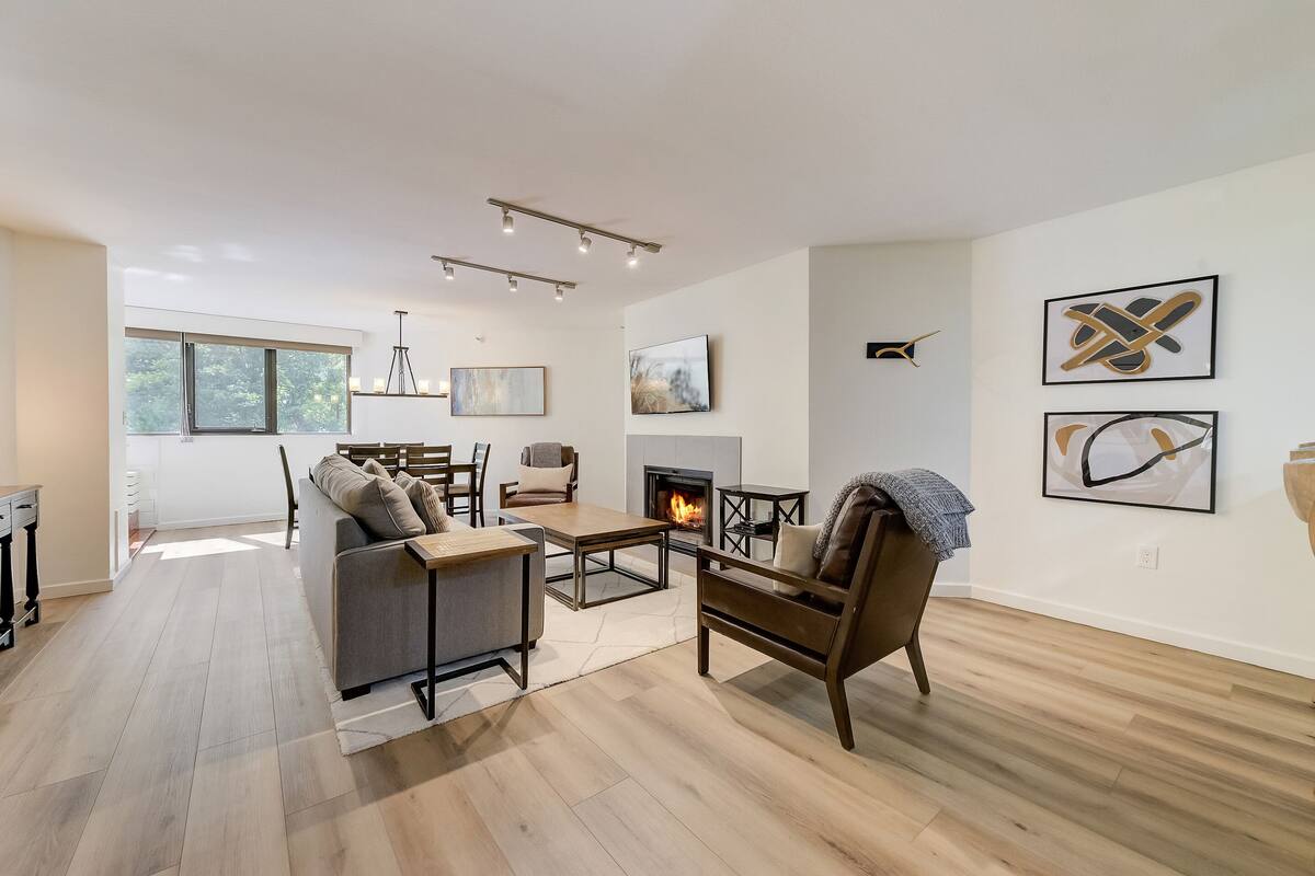 Una sala de estar moderna con chimenea, piso de madera y mobiliario contemporáneo.