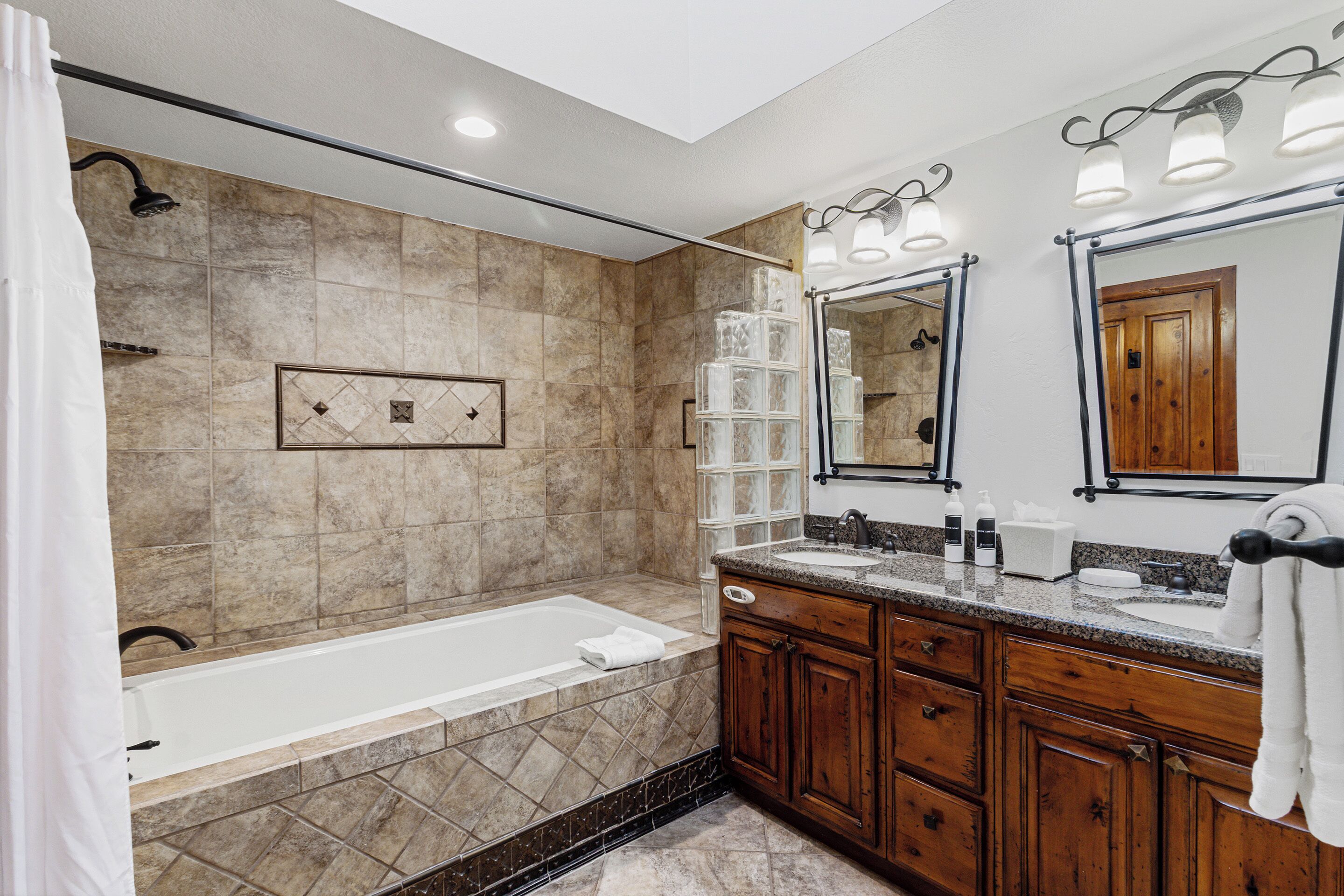 A modern bathroom with a bathtub, vanity with a mirror, and a shower area.