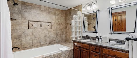 A modern bathroom with a bathtub, vanity with a mirror, and a shower area.