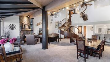 A spacious living area with a wooden staircase, a dining table, and a fireplace.
