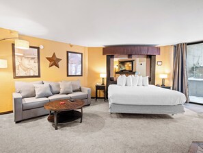 Ein Hotelzimmer mit einer Couch, einem Bett, einem Couchtisch und einem Fernseher.