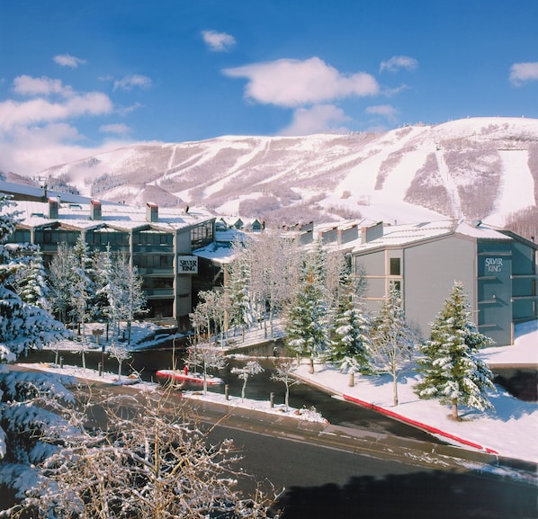 Un complejo turístico nevado con edificios modernos, un telesilla y un río.