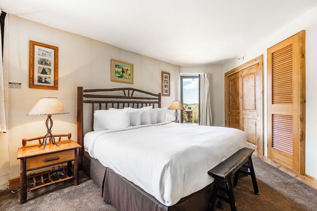 Un dormitorio ordenado con una cama de madera, mesitas de noche y un banco.