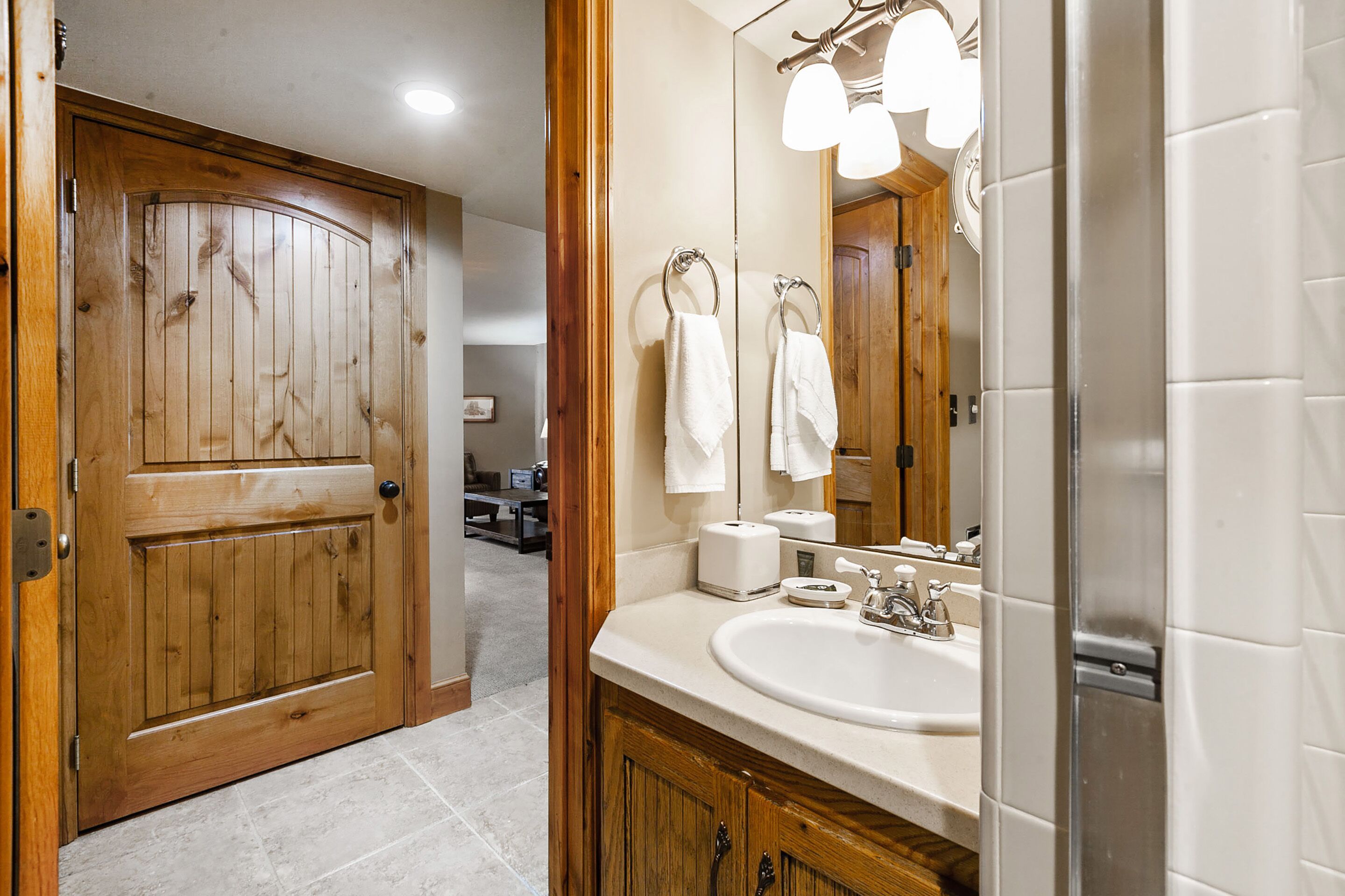 Une salle de bain avec une porte en bois, un lavabo avec un miroir et un espace douche.
