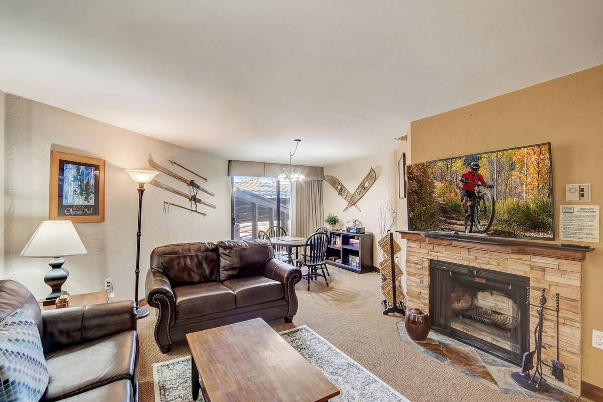 Una sala de estar con chimenea, sofá de cuero y un comedor con sillas y una mesa.