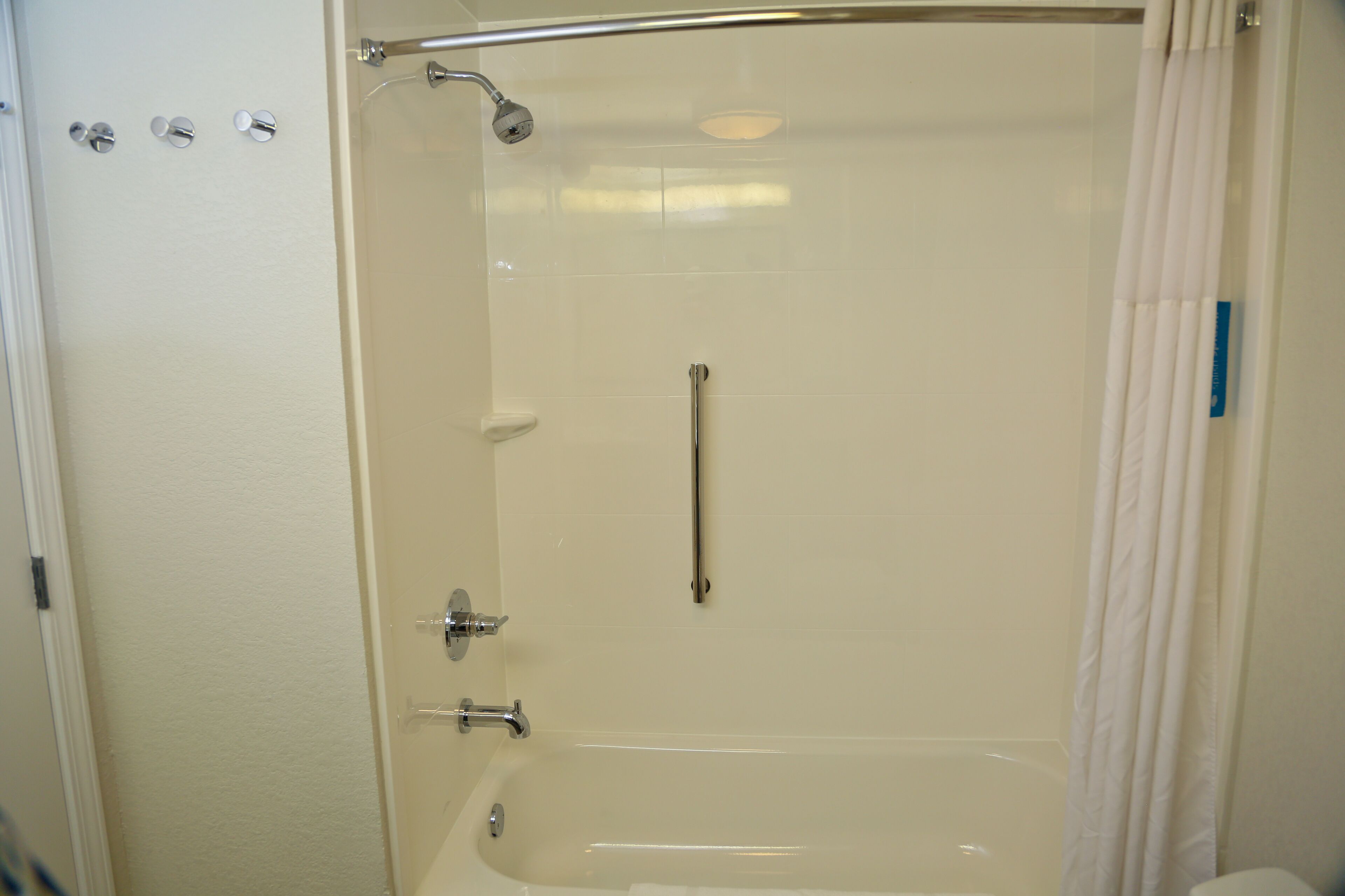 Eine begehbare Dusche mit Glastür, Handbrause und separater Bedienung.