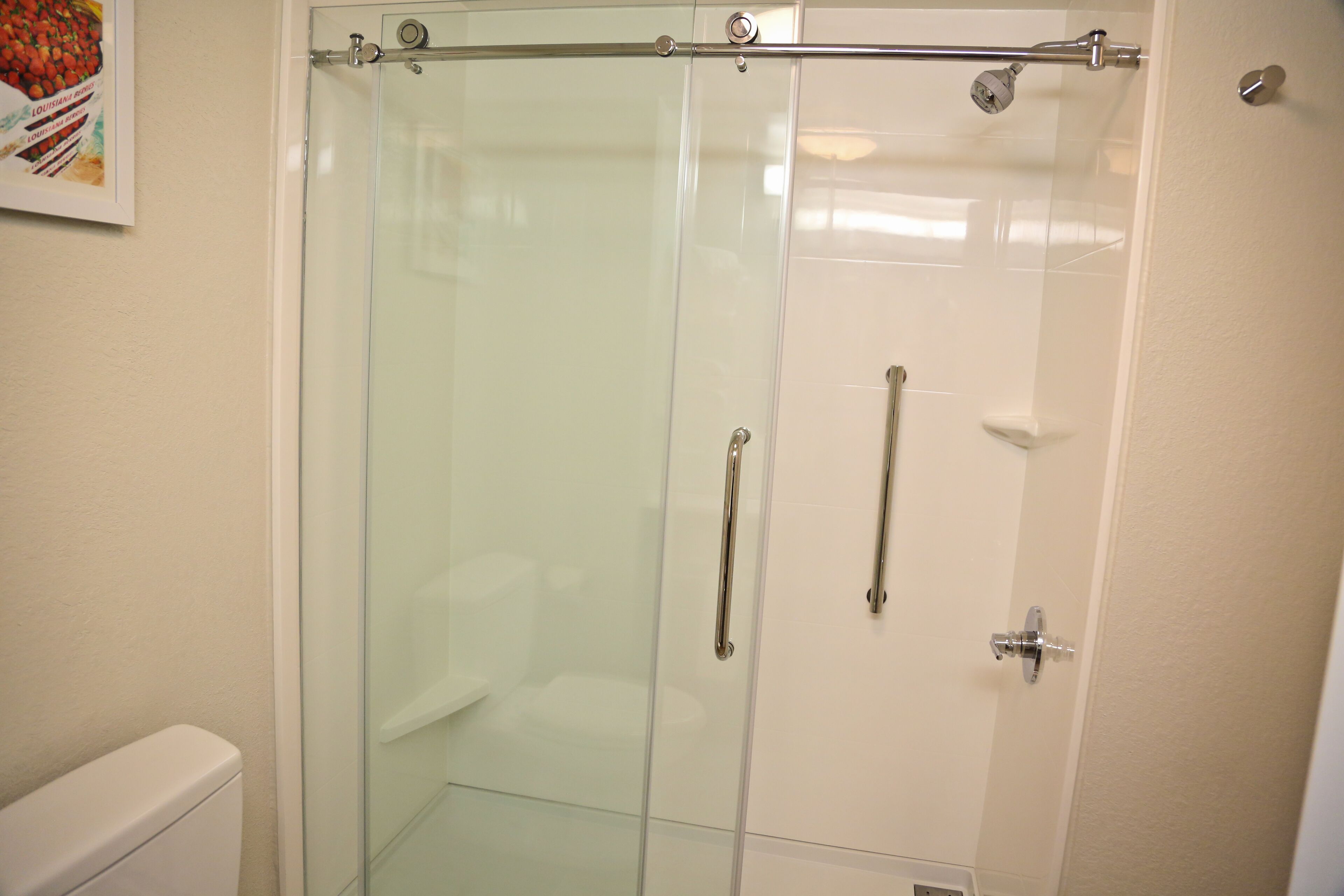 A glass-enclosed shower stall with a metal handle and a showerhead.