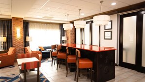 A hotel lobby with a bar area, seating, and a fireplace. - Hampton Inn Hammond (Hammond)