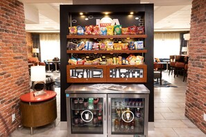 A snack display with various chips and a beverage cooler in a hotel lobby. - Hampton Inn Hammond (Hammond)