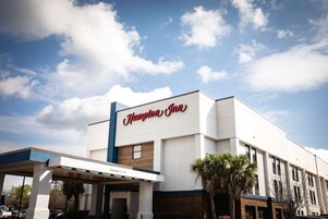 Um hotel Hampton Inn com céu claro e nuvens.