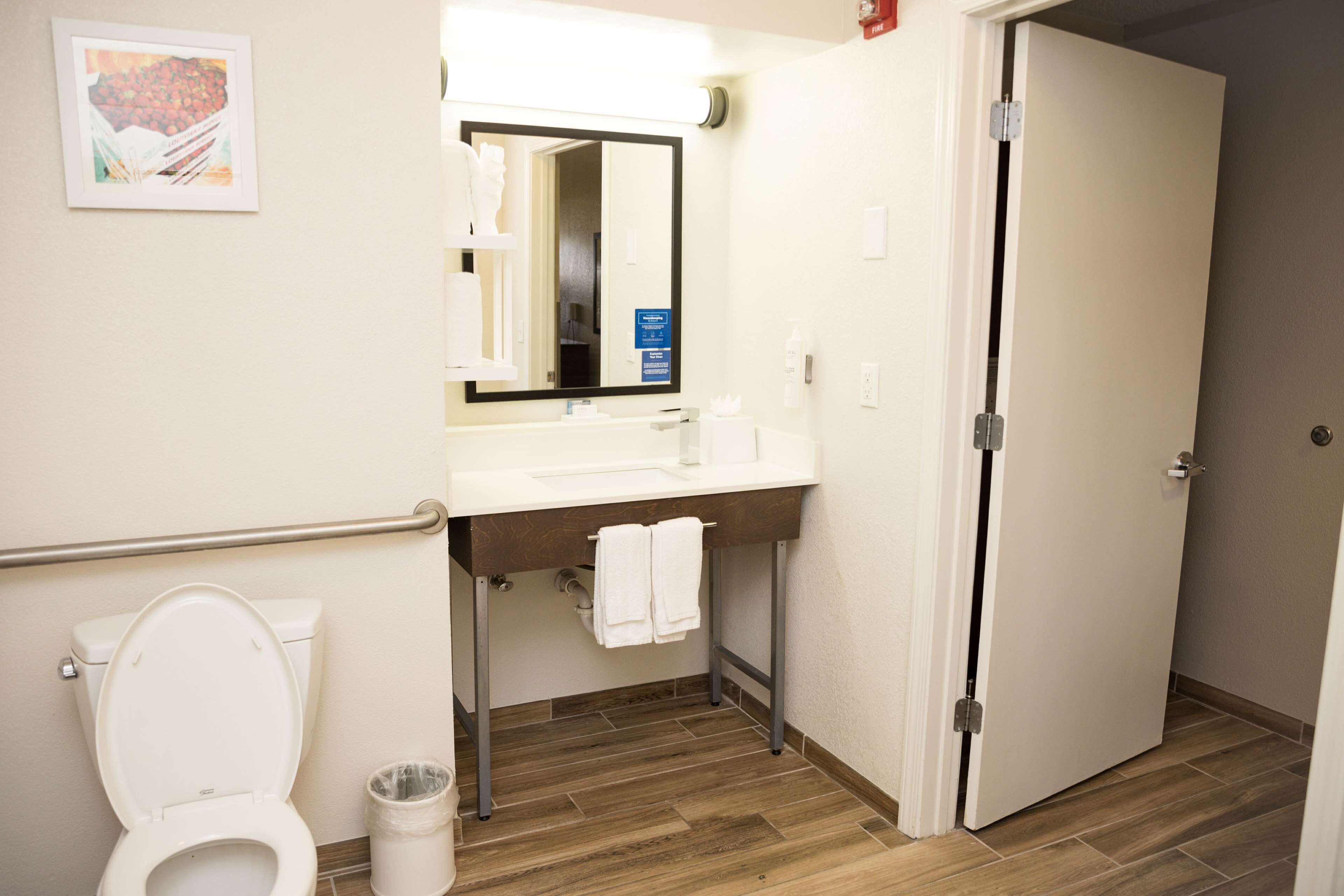 A bathroom with a white toilet, a sink with a mirror, and a door.