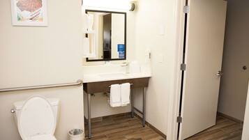 A bathroom with a white toilet, a sink with a mirror, and a door.