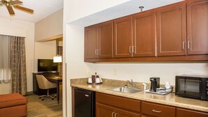 A compact kitchen with wooden cabinets, a sink, a microwave, and a dishwasher. - Hampton Inn Hammond (Hammond)
