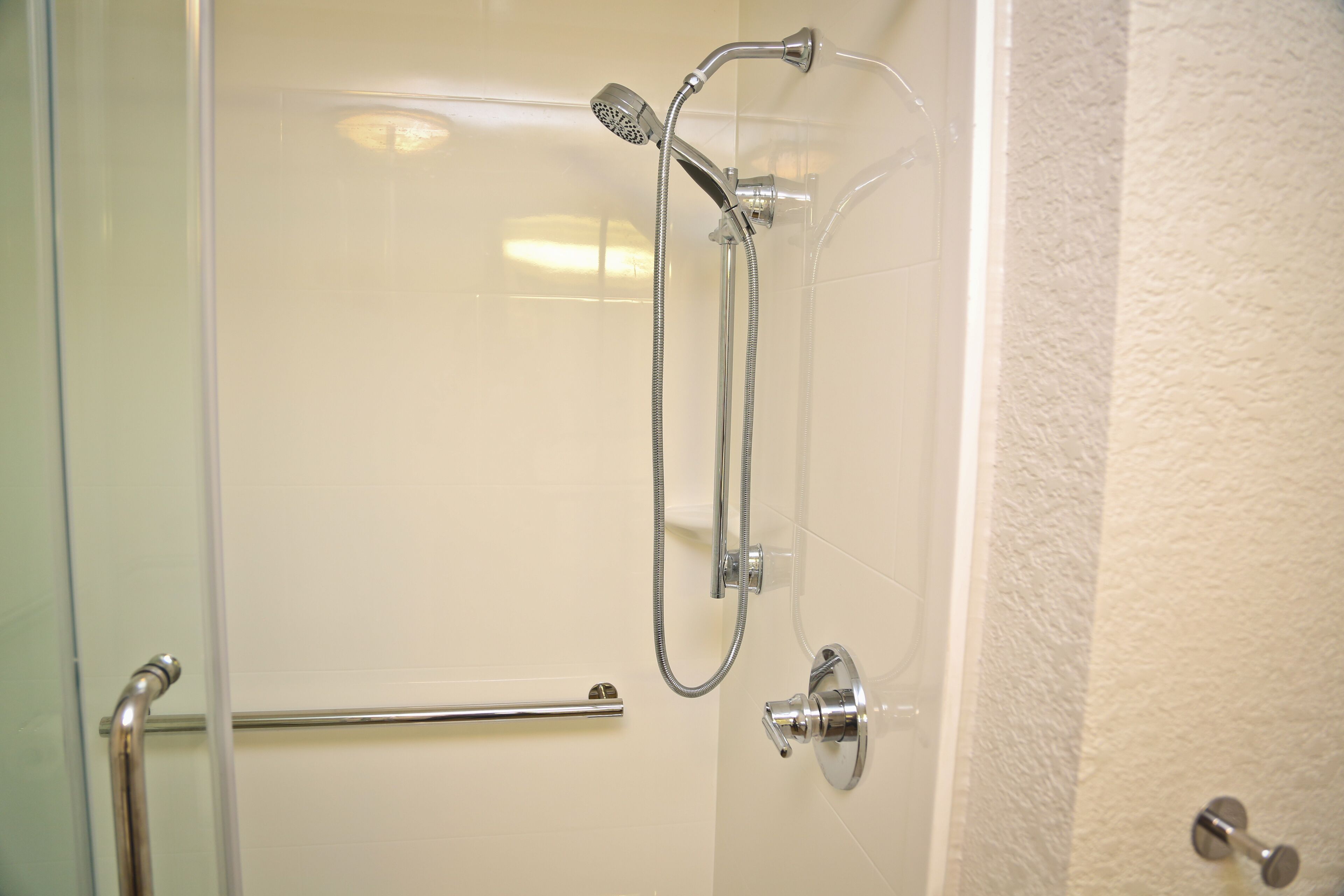 A shower with a handheld showerhead and a wall-mounted faucet.