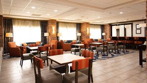 A hotel lobby with multiple seating areas, including sofas and tables, and a projection screen on the wall. - Hampton Inn Hammond (Hammond)