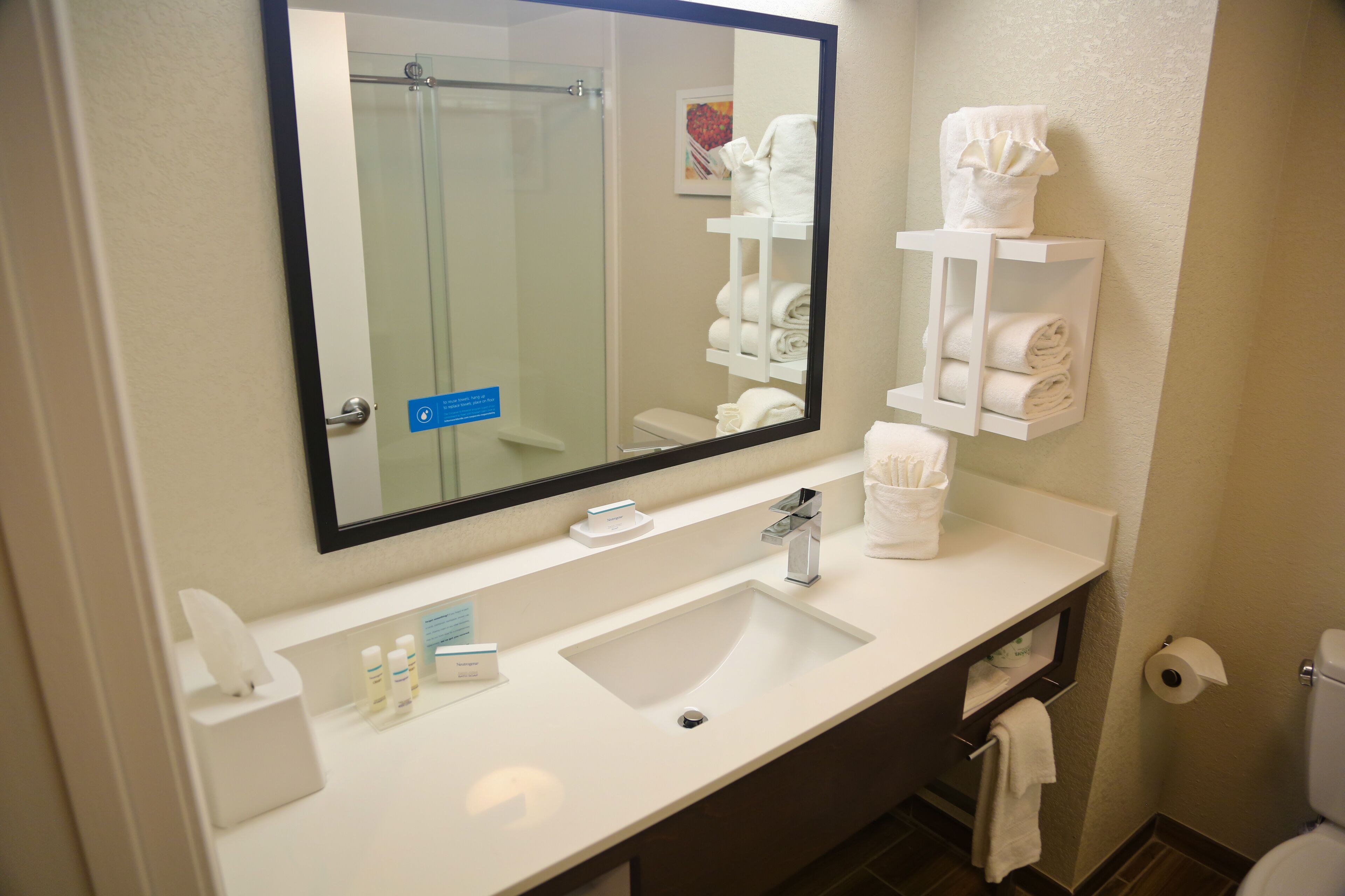 A bathroom with a white sink, a large mirror, and a towel rack.