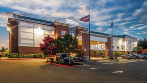 A Sonesta Essential hotel with a brick facade, large windows, and an American flag. - Sonesta Essential Vacaville - Napa Valley (Vacaville)