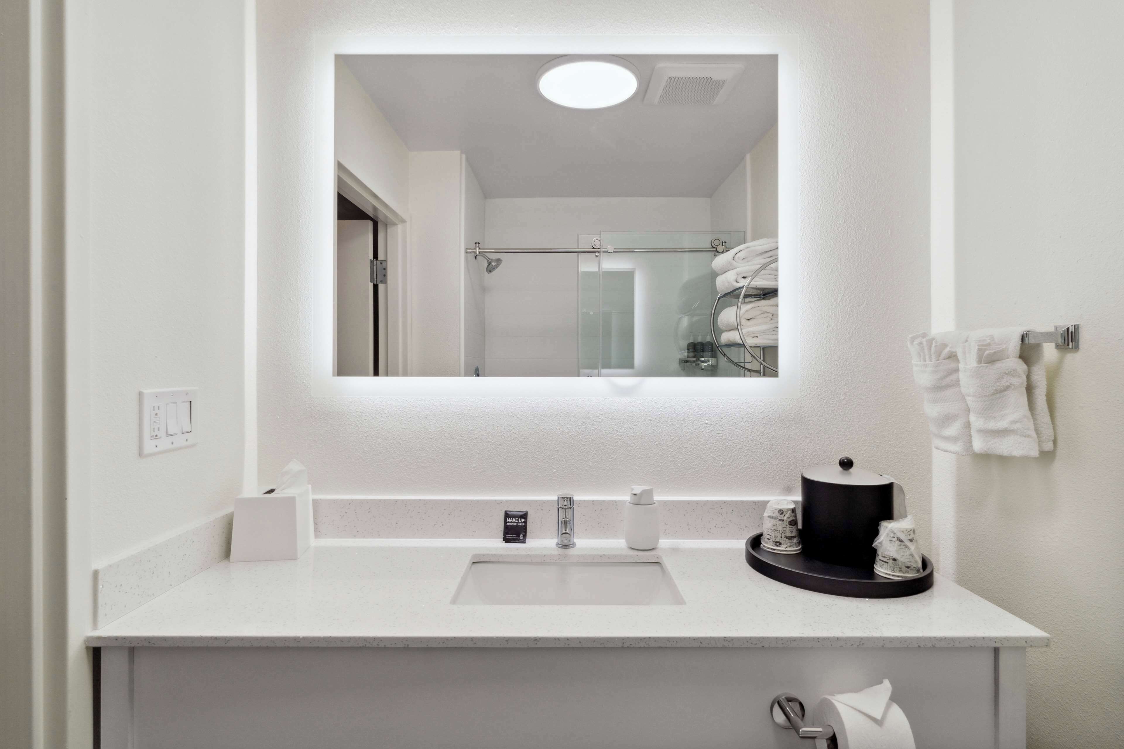 Un baño moderno con un lavamanos blanco, un espejo y una cabina de ducha de vidrio.