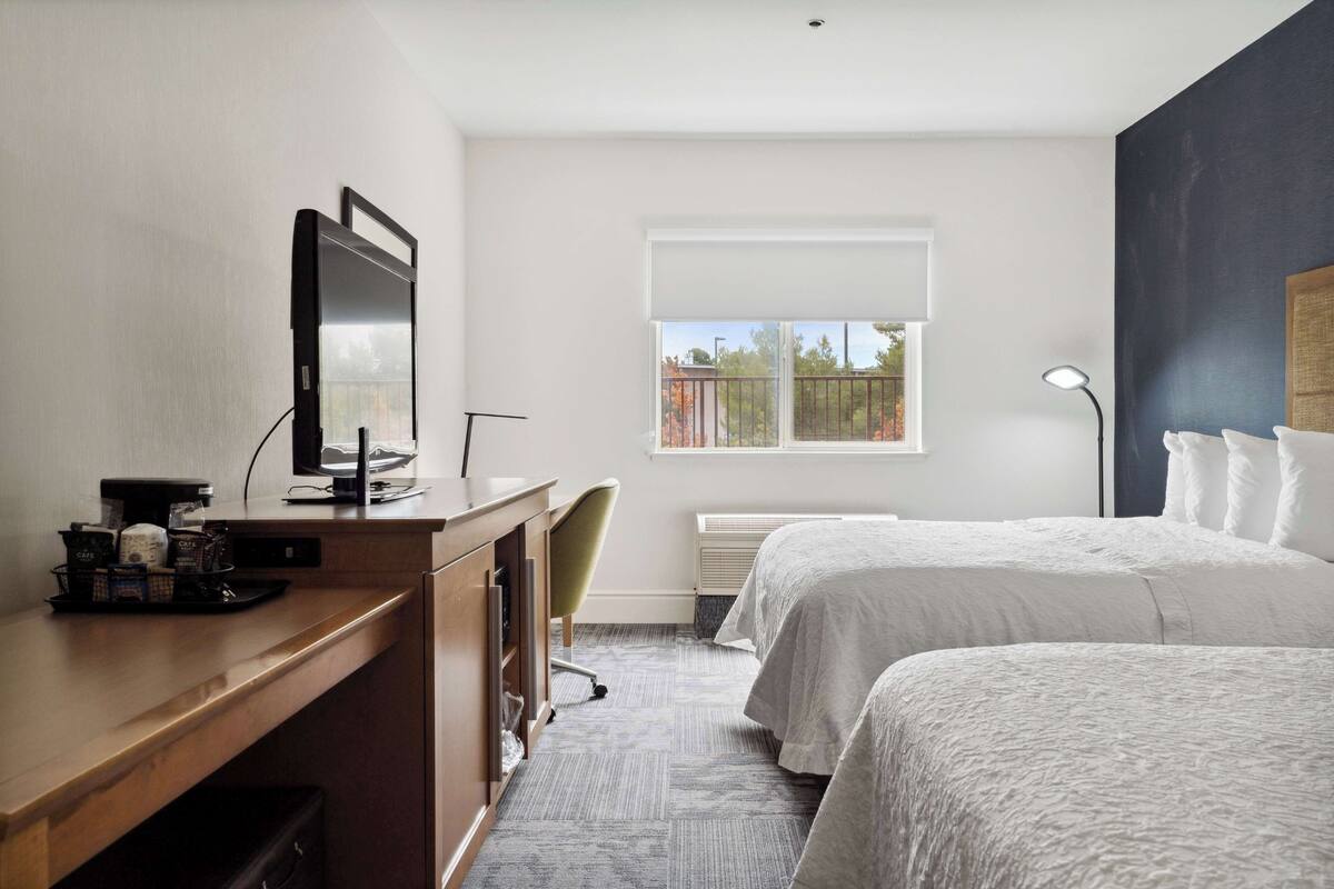 Hotellihuone, jossa on työpöytä, tuoli, sänky, ikkuna ja lamppu.