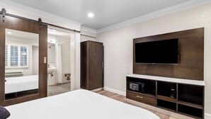 Een moderne slaapkamer met een groot bed, een schuifdeurkast, een wandtelevisie en een ingebouwde televisieplank.