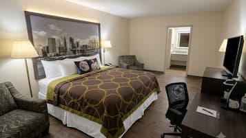 A hotel room with a bed, a desk, a chair, a TV, and a cityscape painting on the wall.
