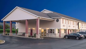 A hotel with a covered entrance, multiple windows, and a parking lot.