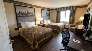 A hotel room with two beds, a desk with a chair, a television, and a window with curtains.
