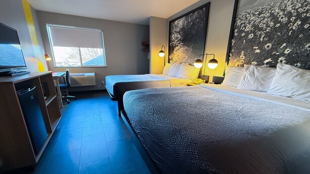 A hotel room with two beds, a desk, a chair, a TV, and a large window. - Super 8 by Wyndham Windsor (Windsor)