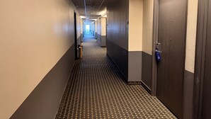 A hotel hallway with a patterned carpet, doors on both sides, and a ceiling with recessed lighting. - Super 8 by Wyndham Windsor (Windsor)