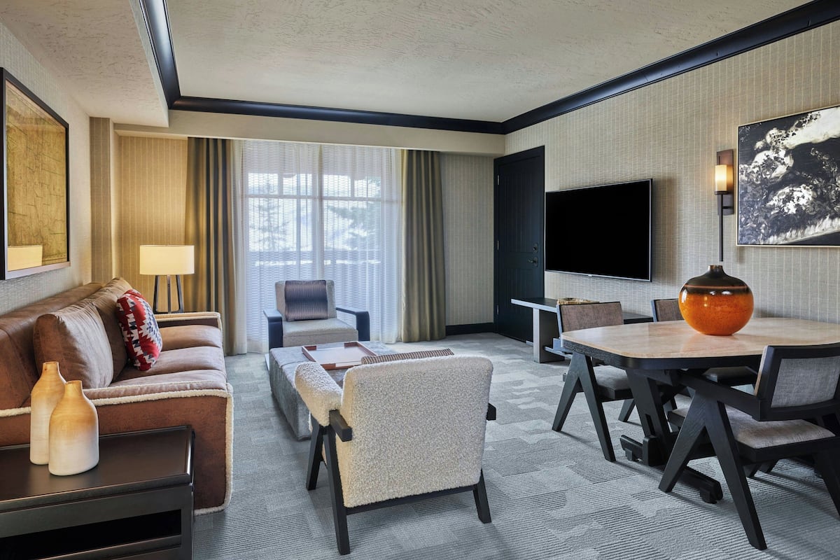 Ein modernes Hotelzimmer mit einer Couch, einem Sessel und einem Esstisch.