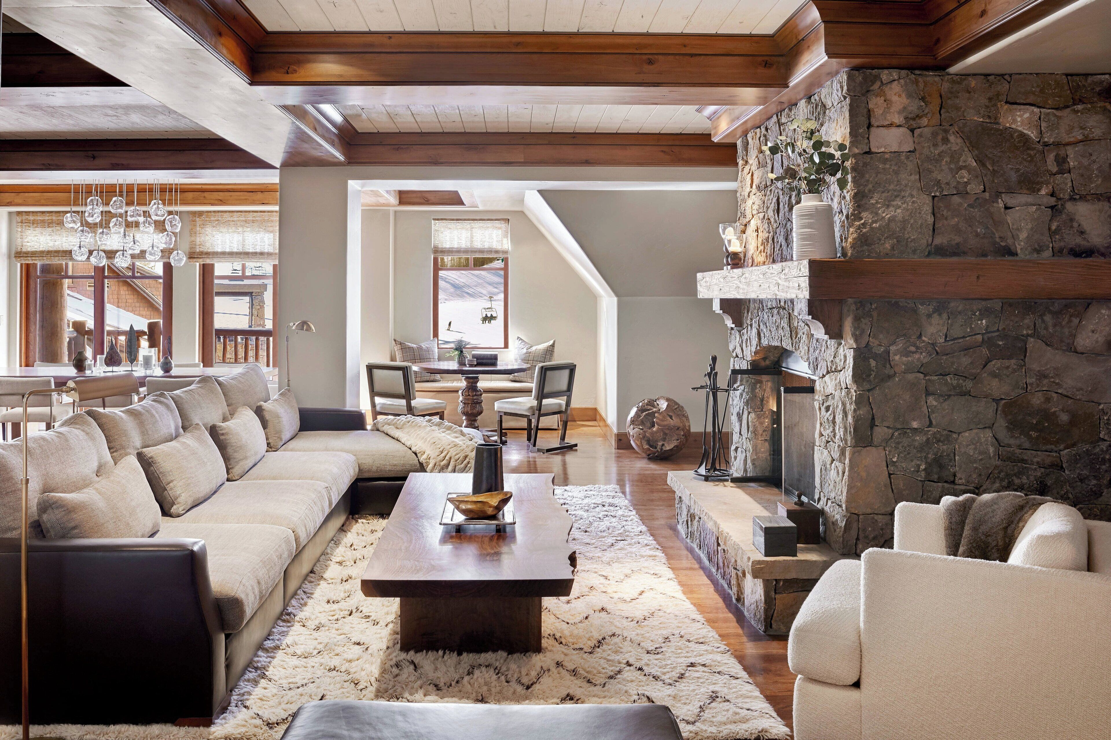 A spacious living room with a stone fireplace, a large sectional sofa, and a dining area with a table and chairs.