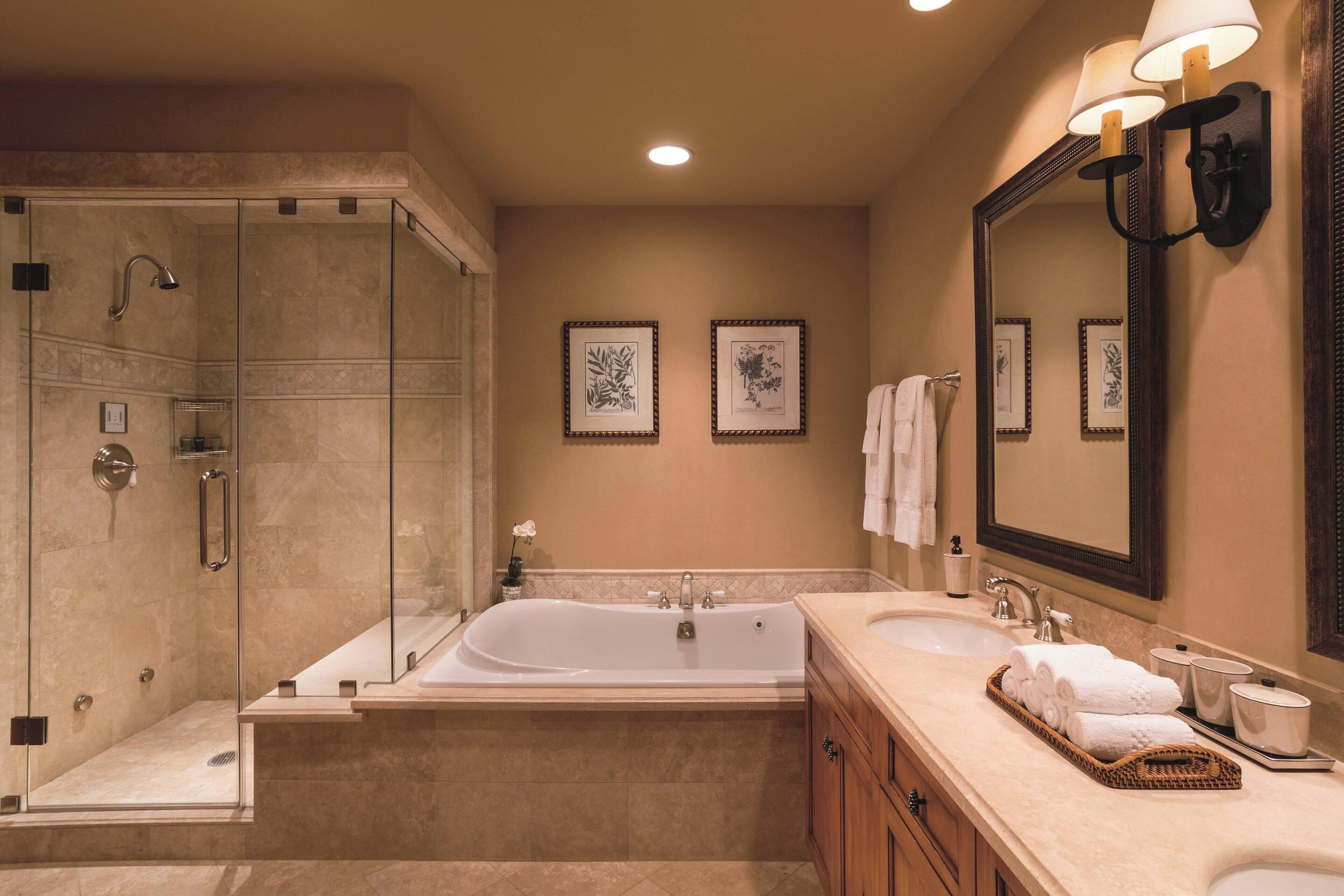 A modern bathroom with a glass-enclosed shower, a freestanding bathtub, and a vanity with a large mirror.