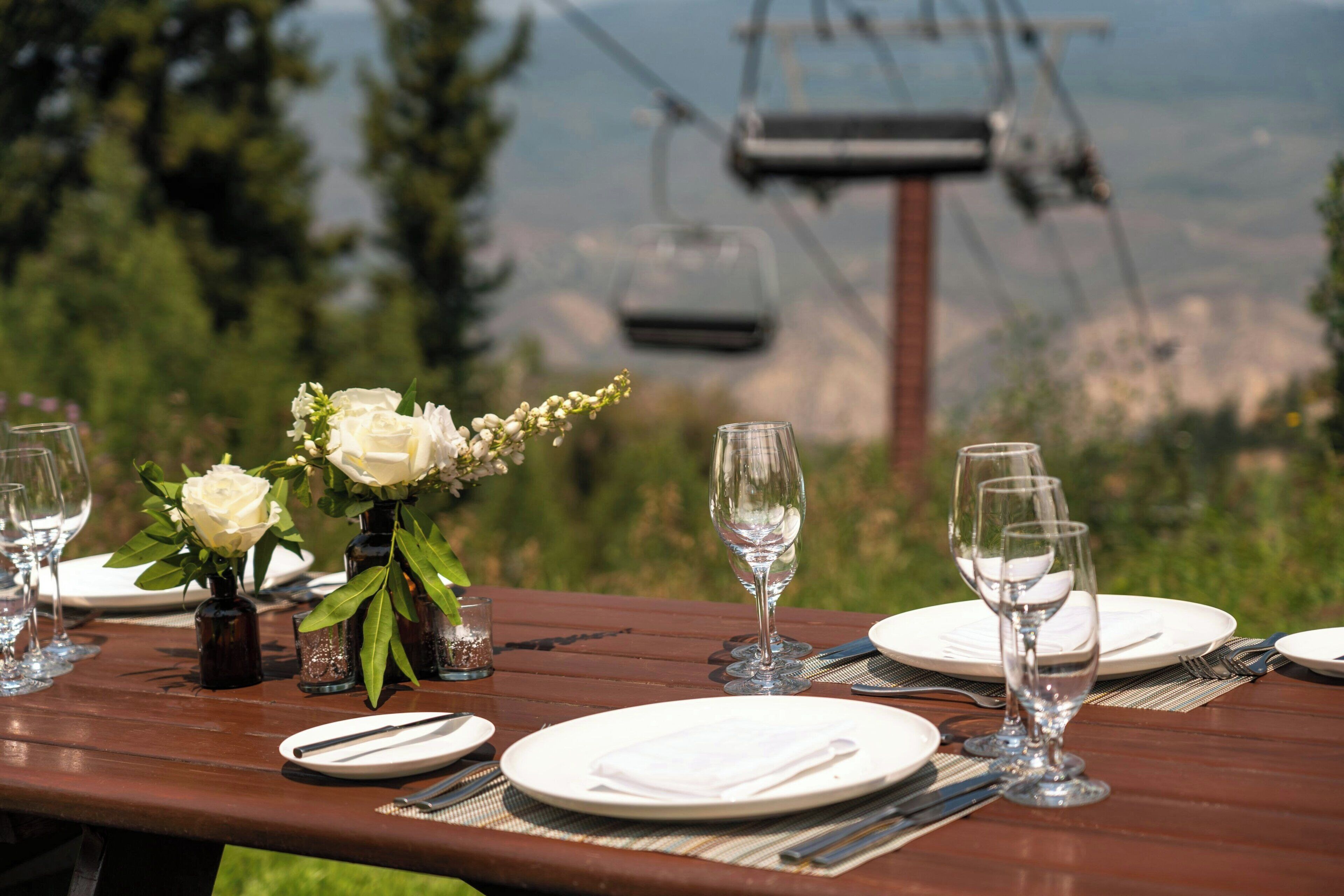 Une table mise pour un repas, avec des assiettes, des couverts et des verres, ainsi qu’un vase rempli de fleurs.