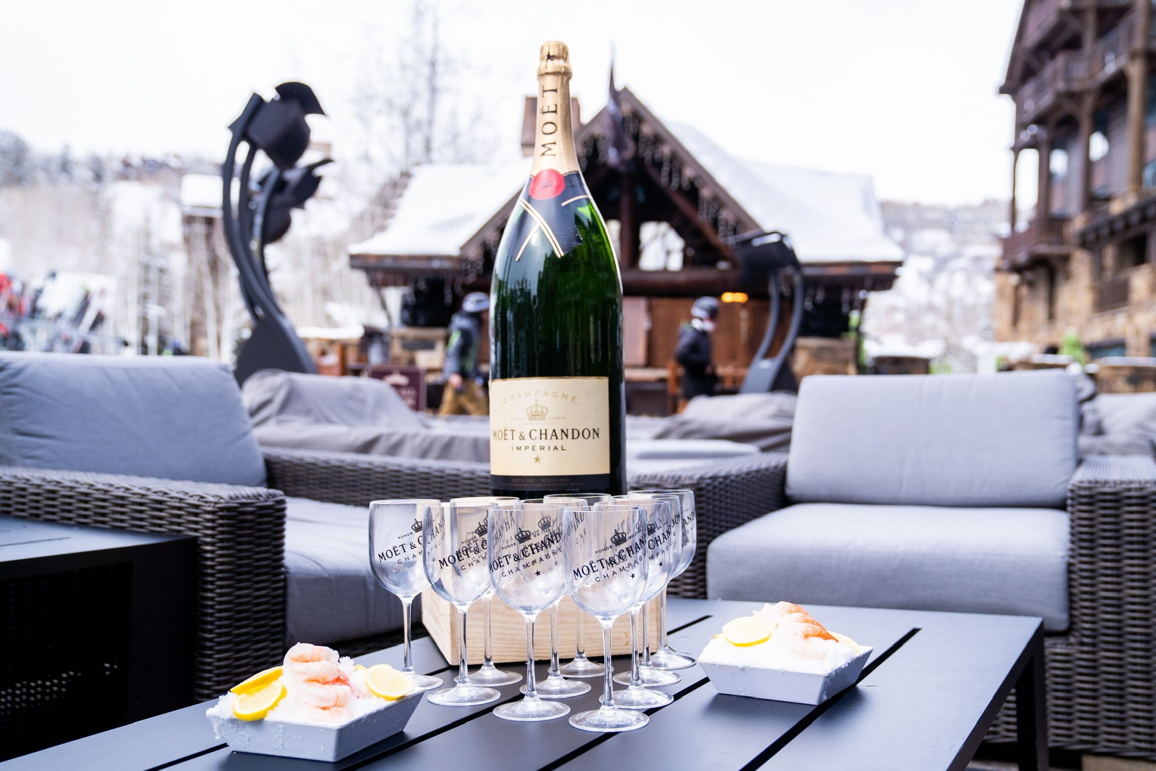 Une bouteille de champagne Moët & Chandon sur une table, avec des verres et des amuse-gueules aux crevettes.