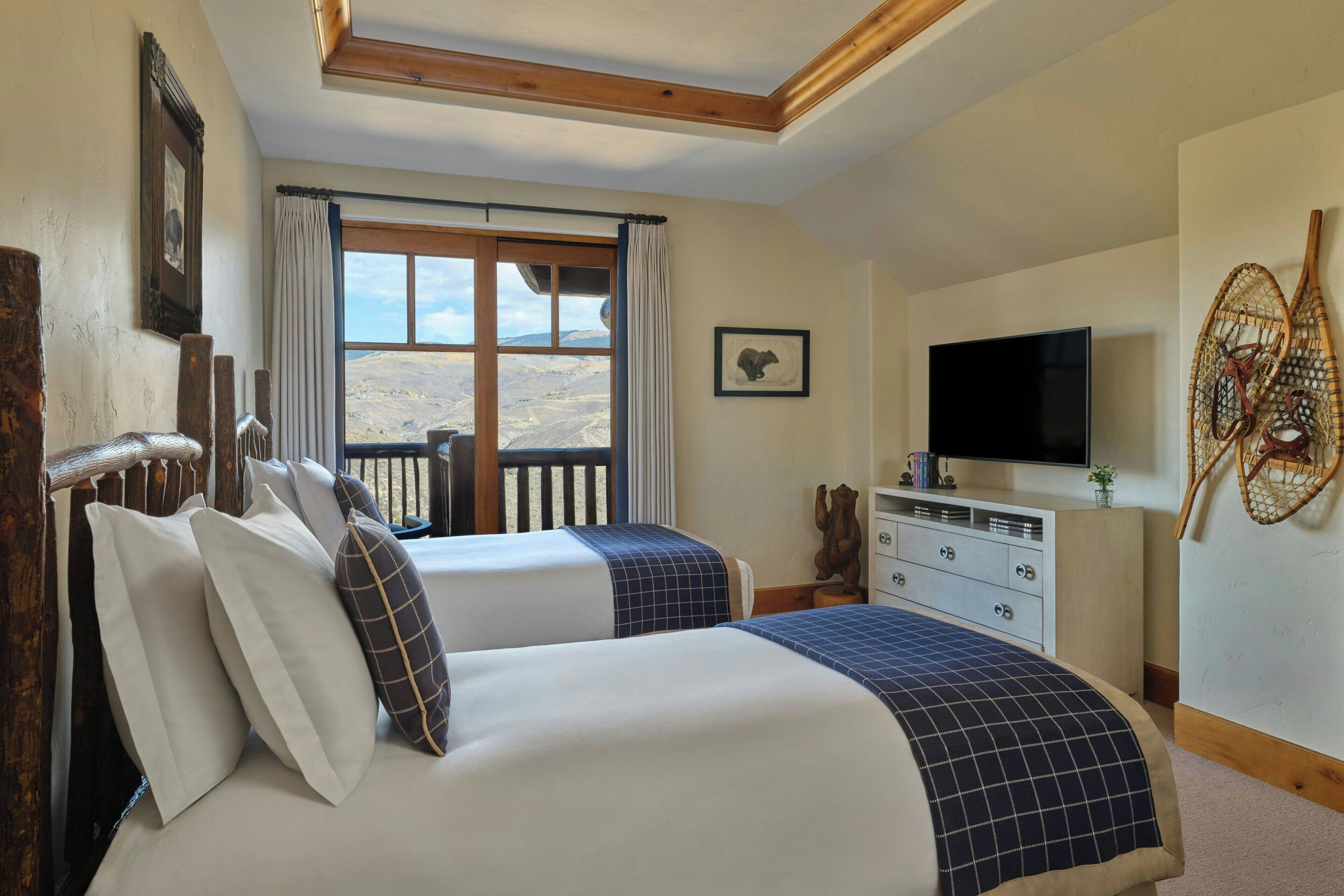 A bedroom with two beds, a TV, a dresser, and a window with a view.