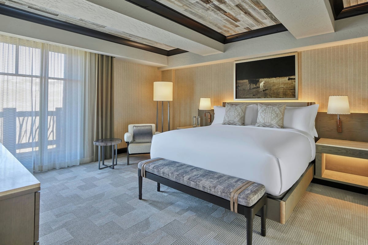 Ein Hotelzimmer mit einem großen Bett, einer Bank, einem Sessel und einem Schreibtisch.