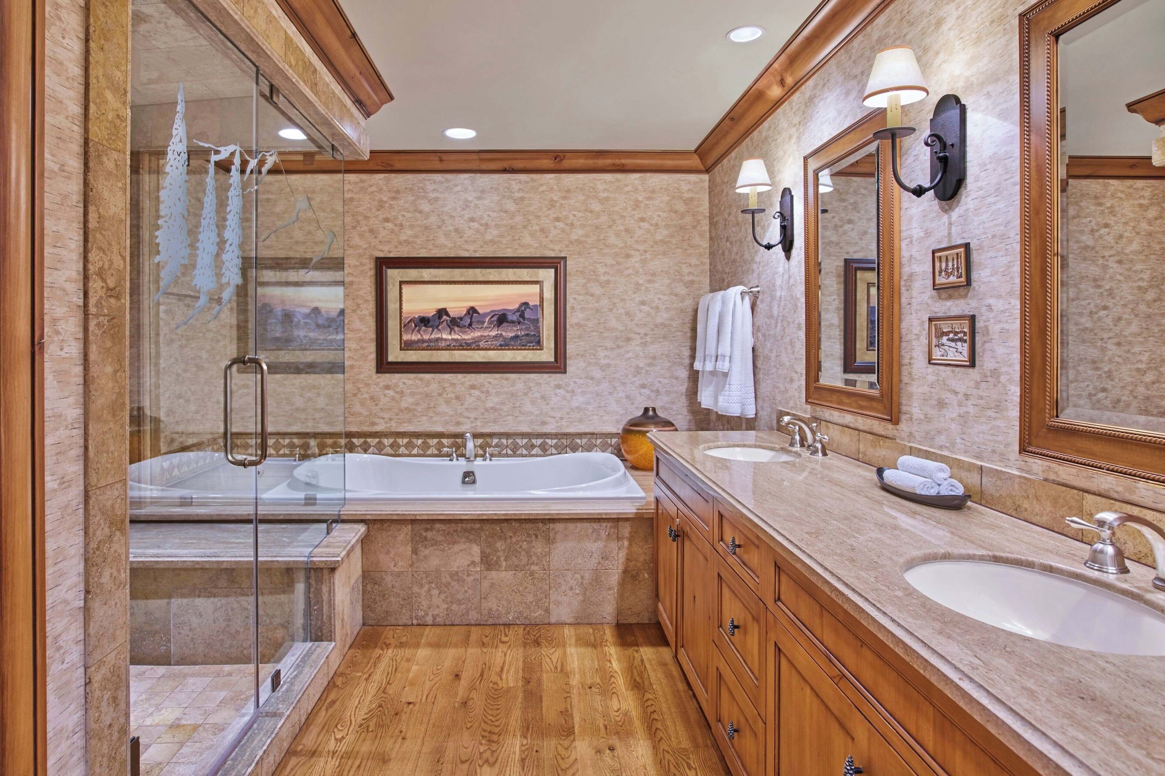 A spacious bathroom with a large bathtub, two sinks, and a glass shower enclosure.