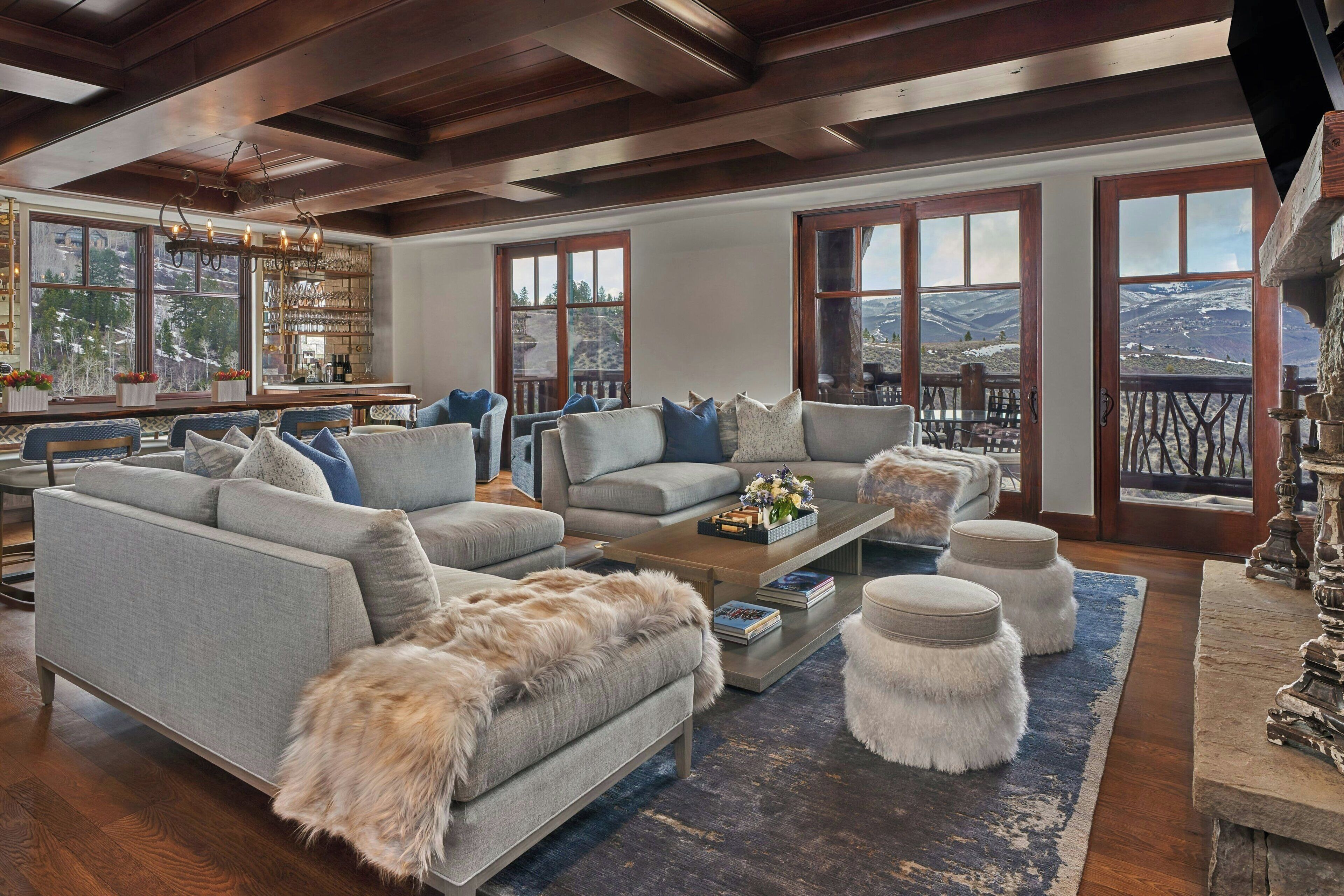 Un salon spacieux avec un grand canapé, une table basse et une cheminée. De grandes fenêtres offrent une vue sur les montagnes.