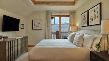 A bedroom with a large bed, a TV mounted on the wall, a wooden dresser, and a balcony with a view.