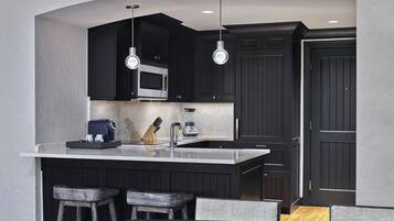A modern kitchen with dark cabinetry, a large island with bar stools, and pendant lighting.