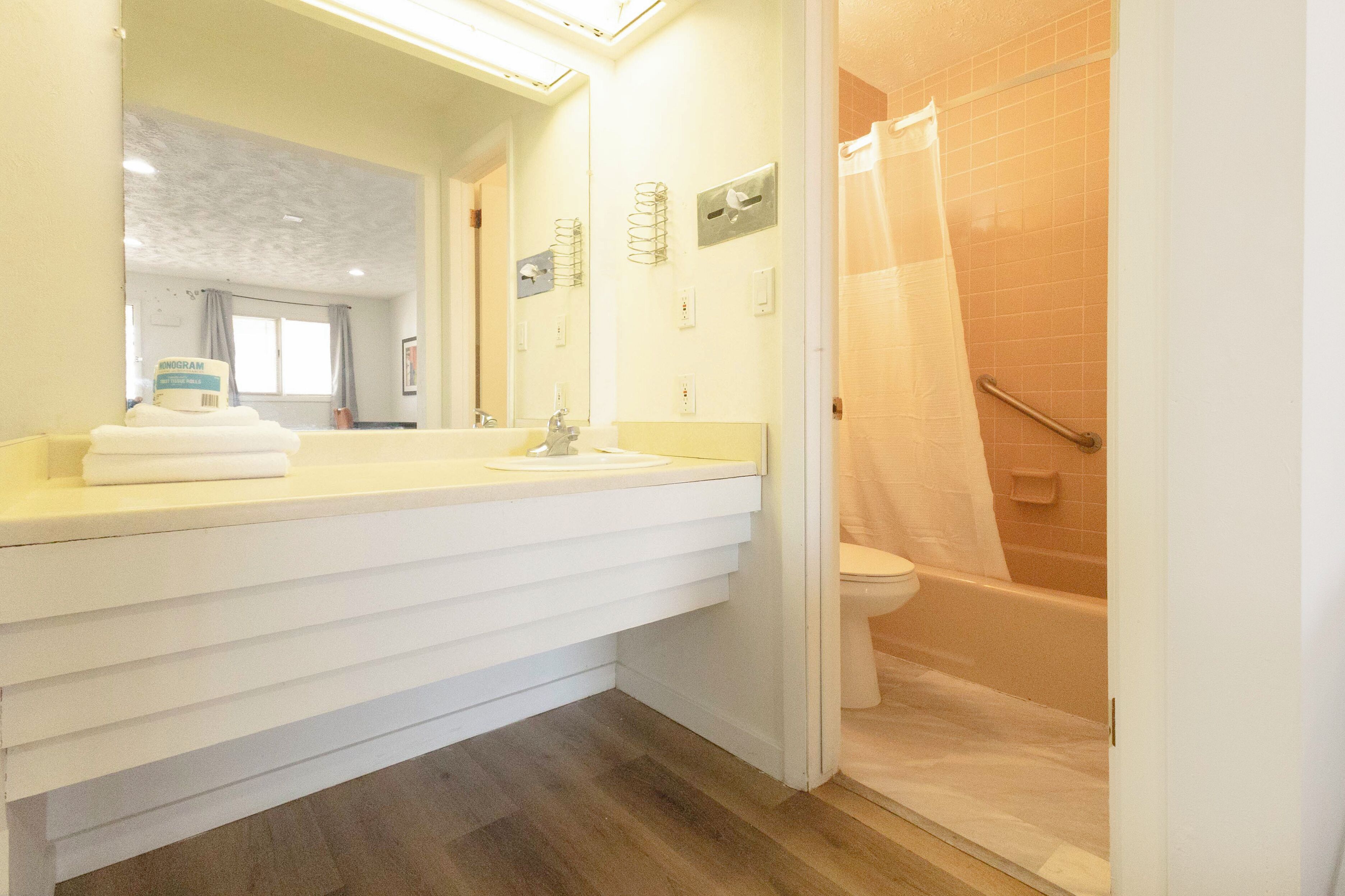 A bathroom with a white vanity, a toilet, and a shower area.