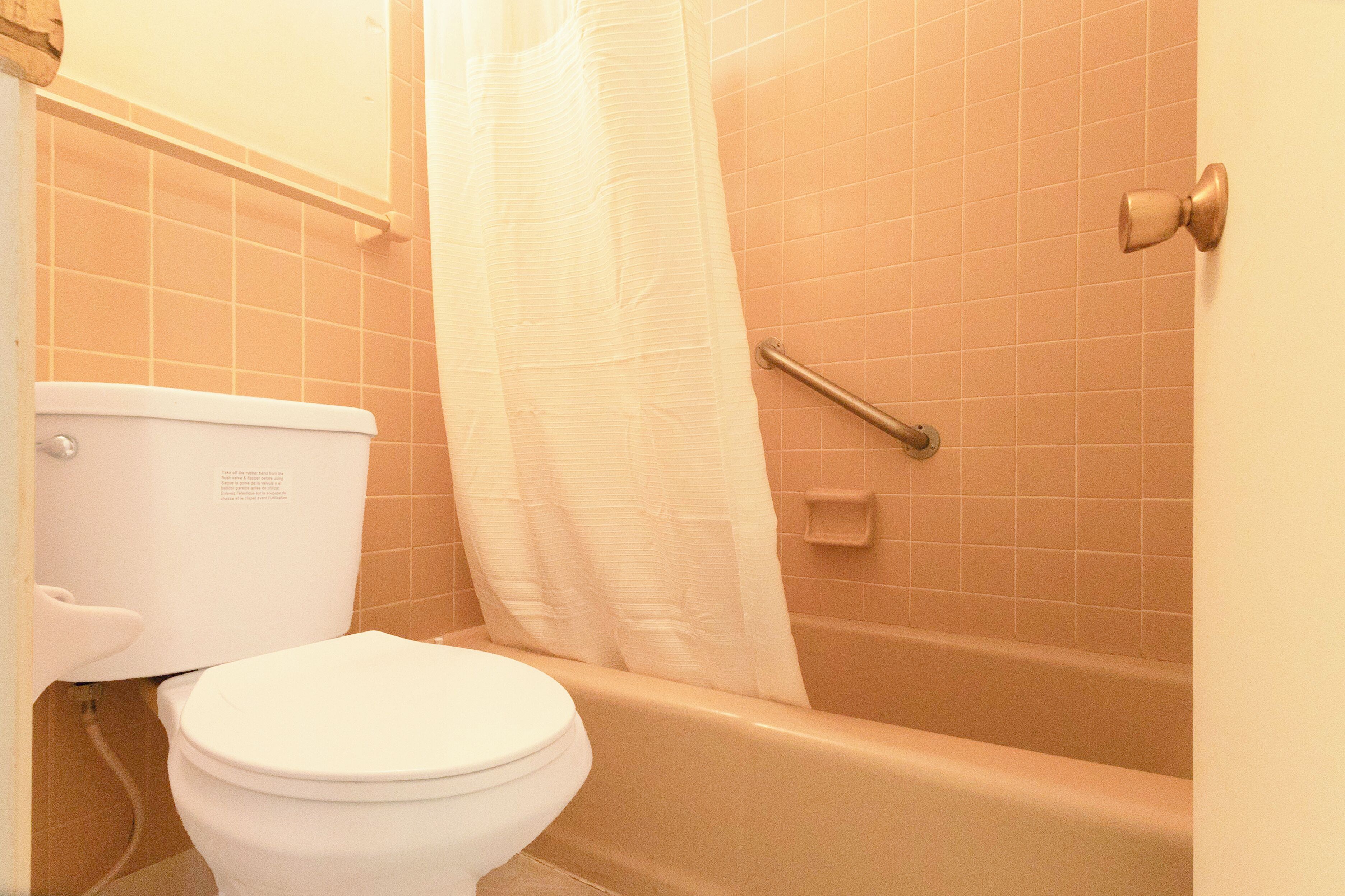 Un baño con inodoro blanco, bañera y cortina de ducha.