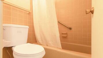 Un baño con inodoro blanco, bañera y cortina de ducha.