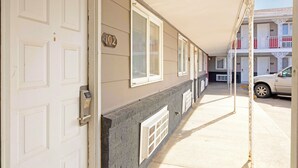 A building with a numbered door, windows, and a car parked outside. - Circle S Motel Cozad I-80 (Cozad)