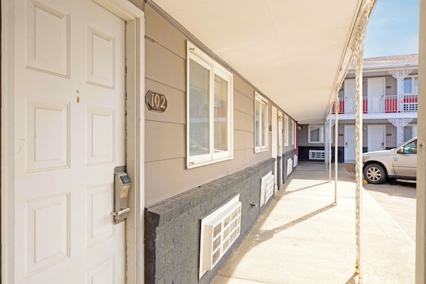 A building with a numbered door, windows, and a car parked outside. - Circle S Motel Cozad I-80 (Cozad)
