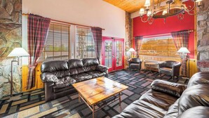 A cozy living room with a leather sofa, a wooden coffee table, and a stone wall. - Quality Inn Payson (Payson)