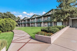 A row of motel buildings with a paved walkway and manicured lawns.