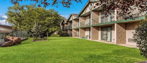 A courtyard with a well-maintained lawn, a stone pathway, and a building with multiple balconies.